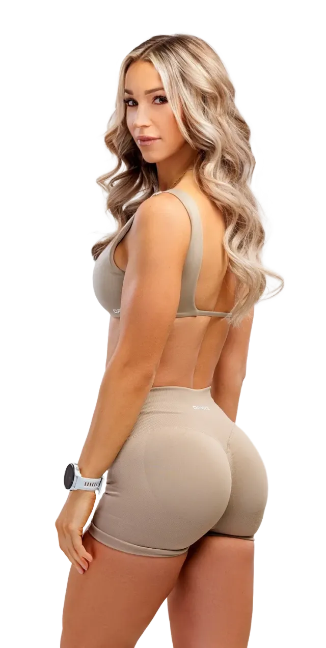 Woman posing in a beige athletic outfit, viewed from the side against a white background.