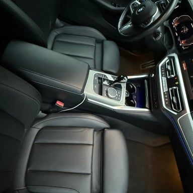 Interior view of a black leather car with a center console, steering wheel, and dashboard.