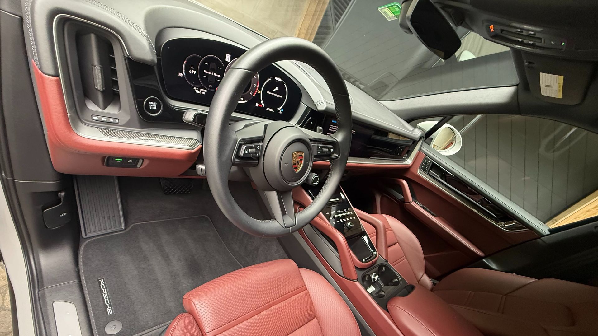 Interior of a Porsche car with red leather seats, black steering wheel, and digital display.