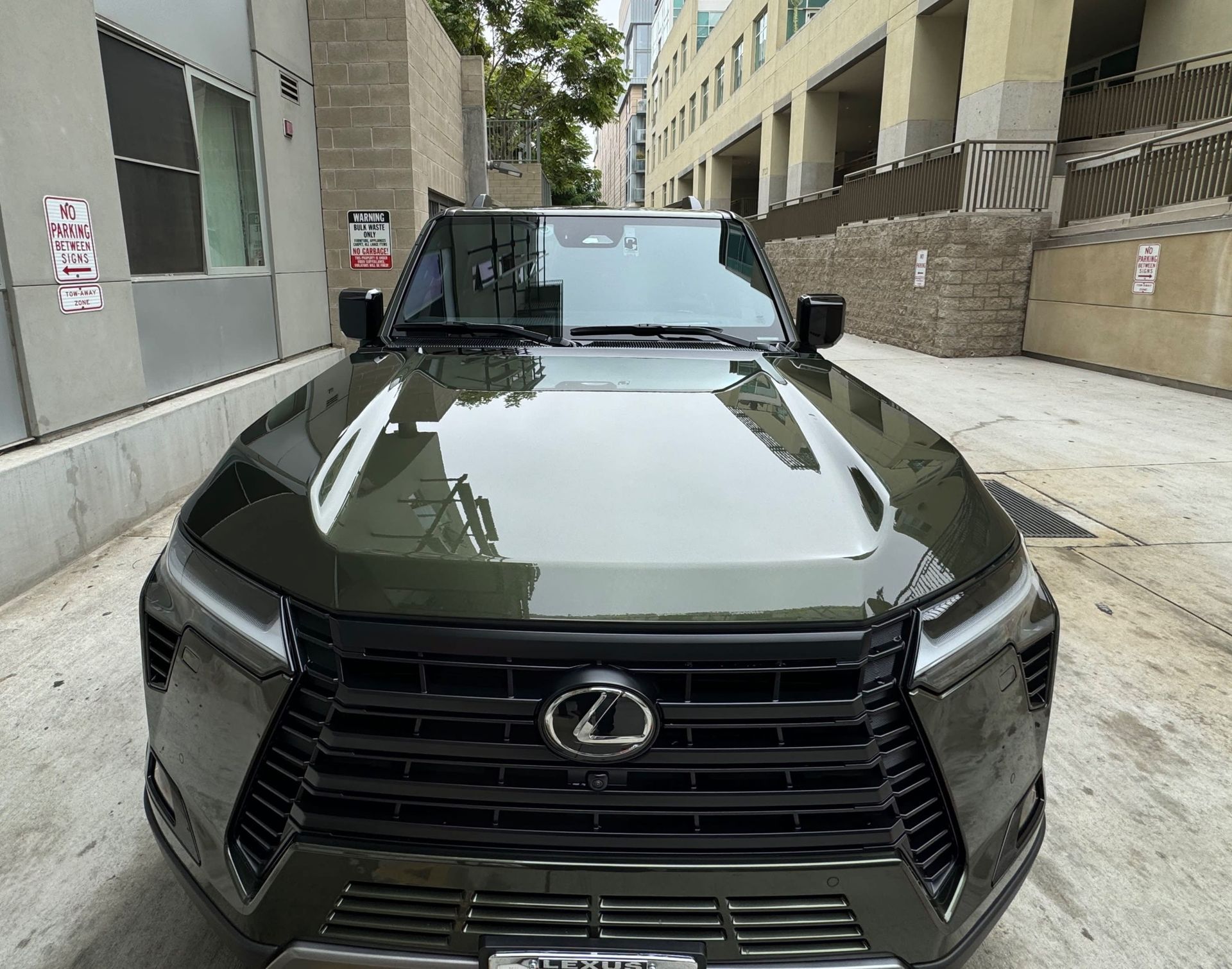 Green Lexus SUV parked in an alleyway.