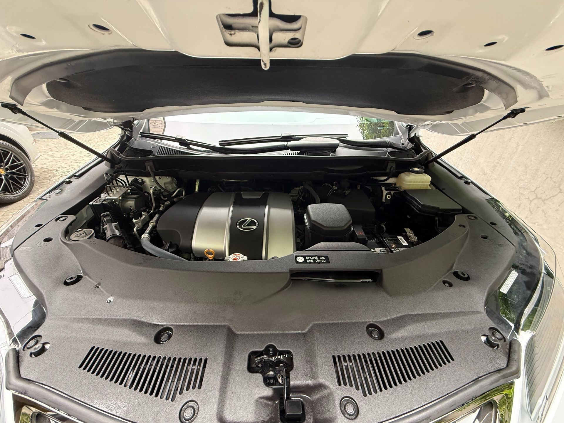 Open car hood revealing engine compartment. Black and silver engine visible.