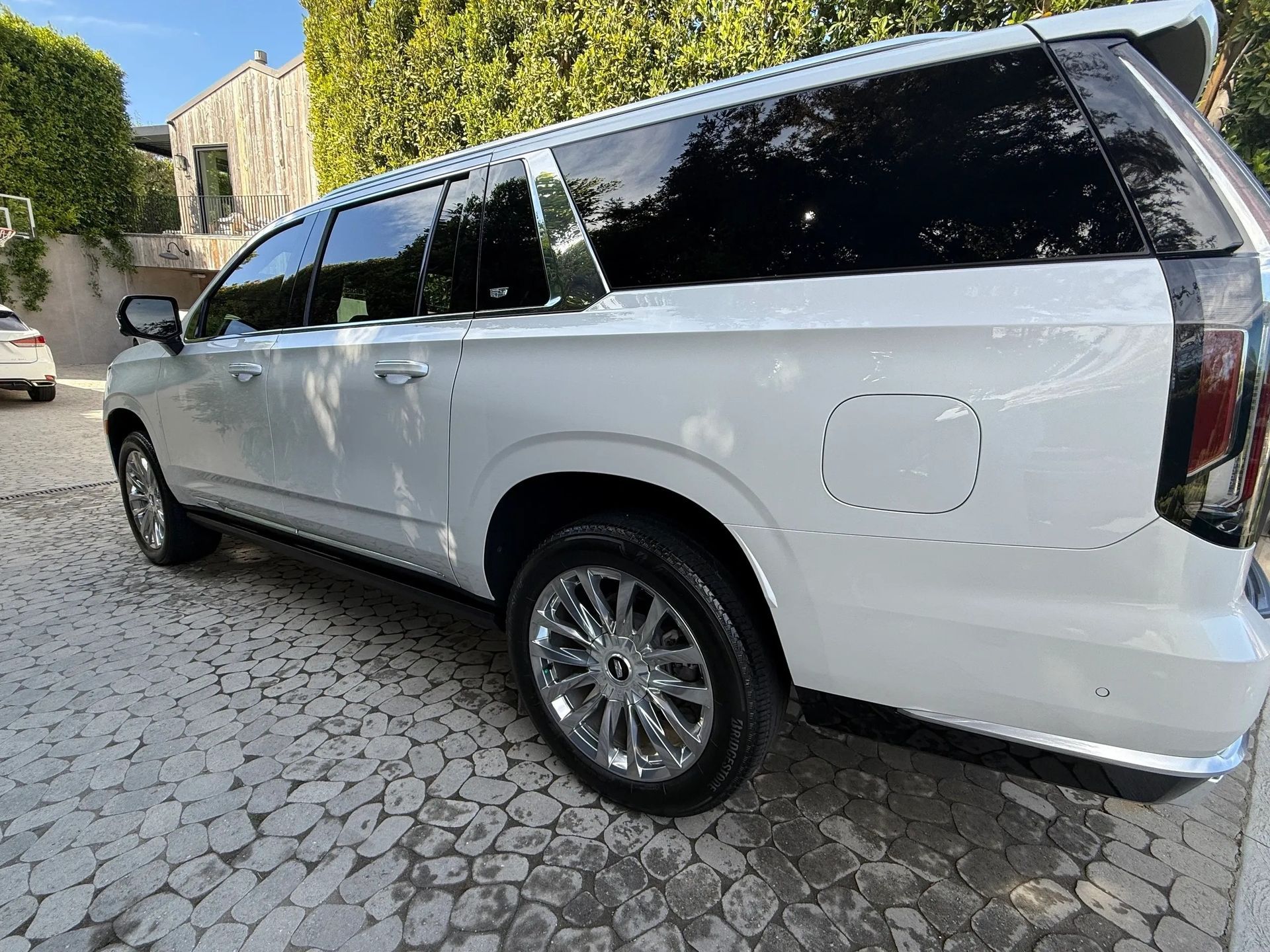 White SUV parked on a cobblestone street, chrome wheels, tinted windows, sunny outdoor setting.
