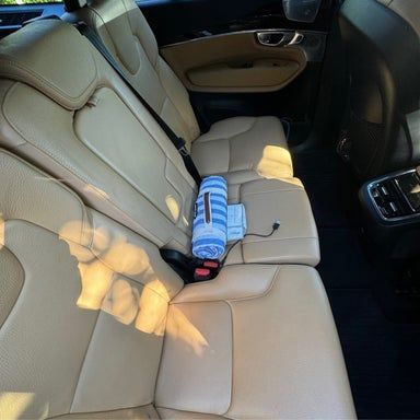 Tan leather car seats with a towel and cord.