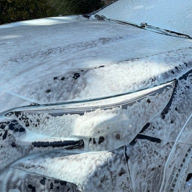 Car covered in white foam during a wash.