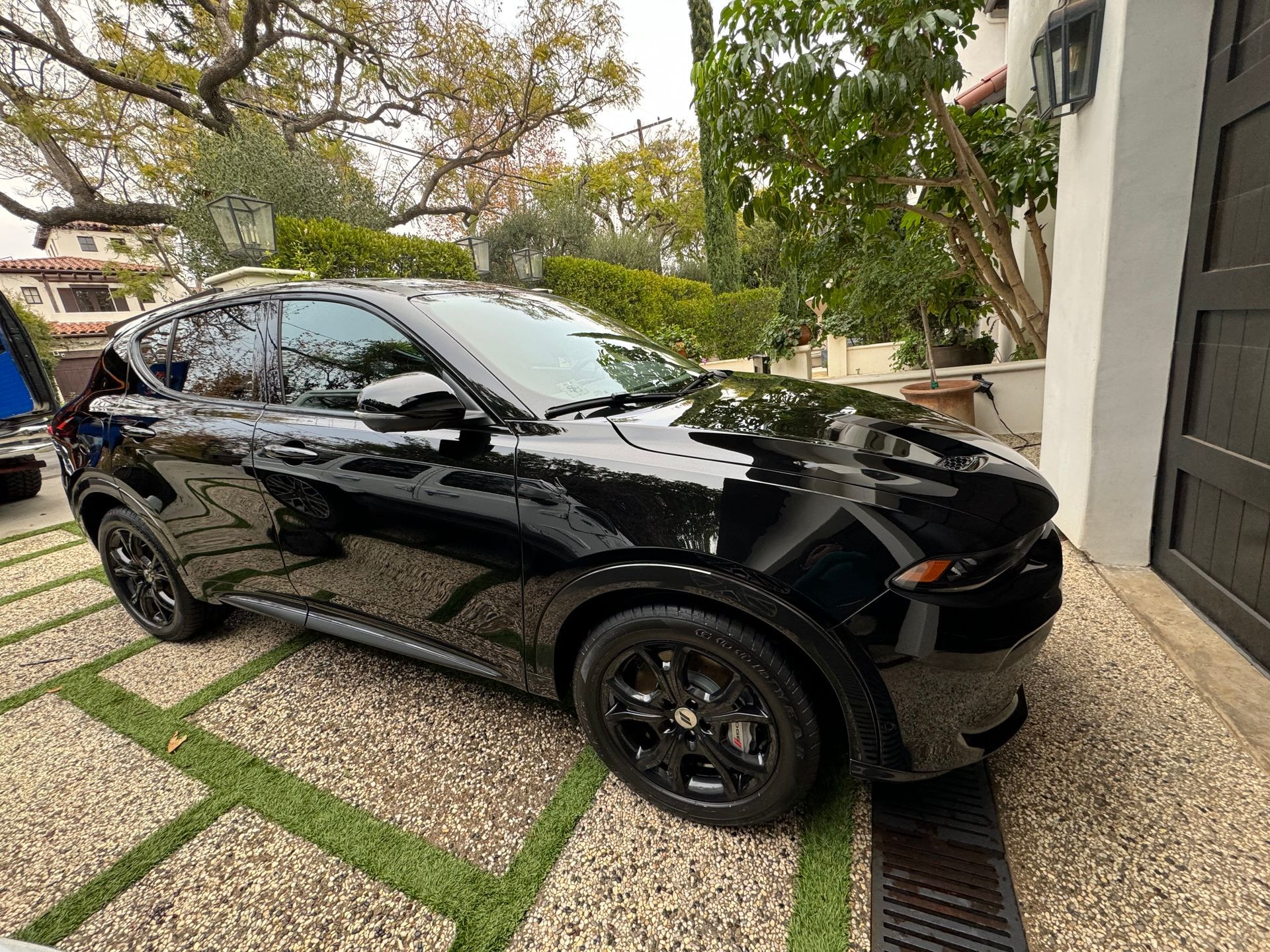 Black SUV parked on a stone driveway next to a building; overcast day.