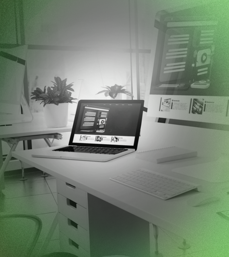 Laptop on white desk in office setting with a keyboard, monitors, and plants.