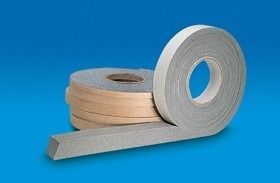 Rotoli di bordatura grigia e beige con un pezzo steso su uno sfondo blu.