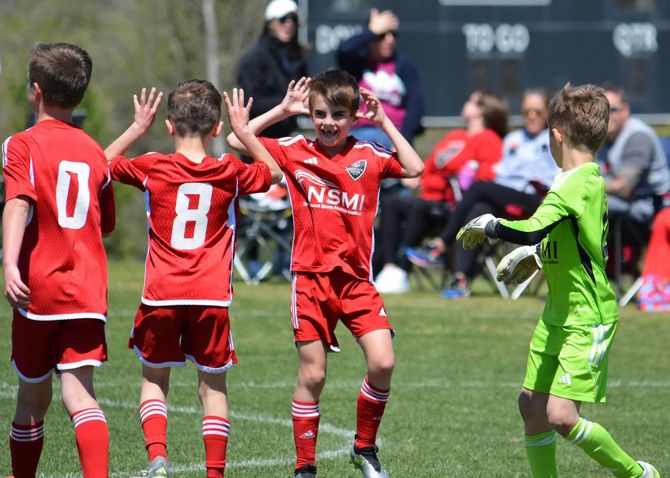 A group of young Loudoun Soccer boys are playing soccer on a field.