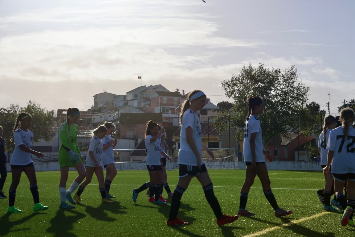 A group of young Loudoun Soccer girls are walking on a soccer field.