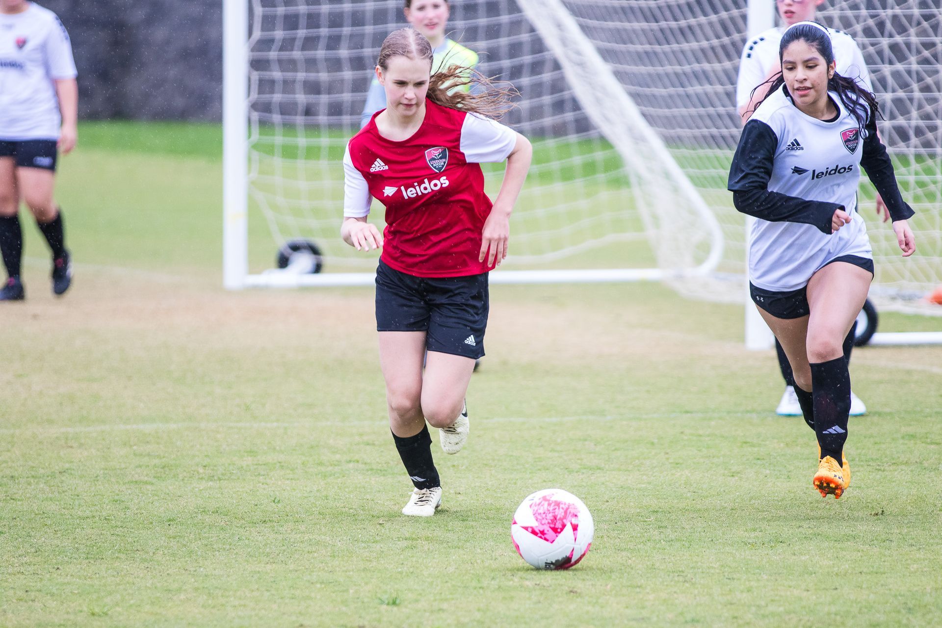 A group of young Loudoun Soccer women are playing soccer on a field.