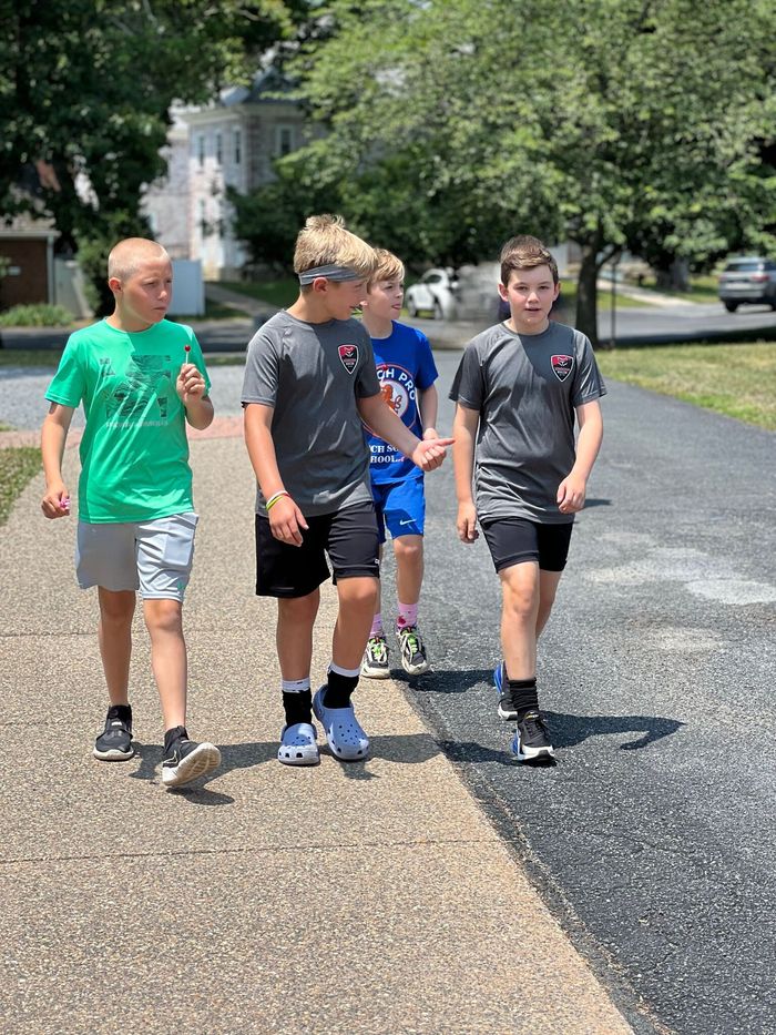 A group of young Loudoun Soccer boys are walking down a sidewalk.