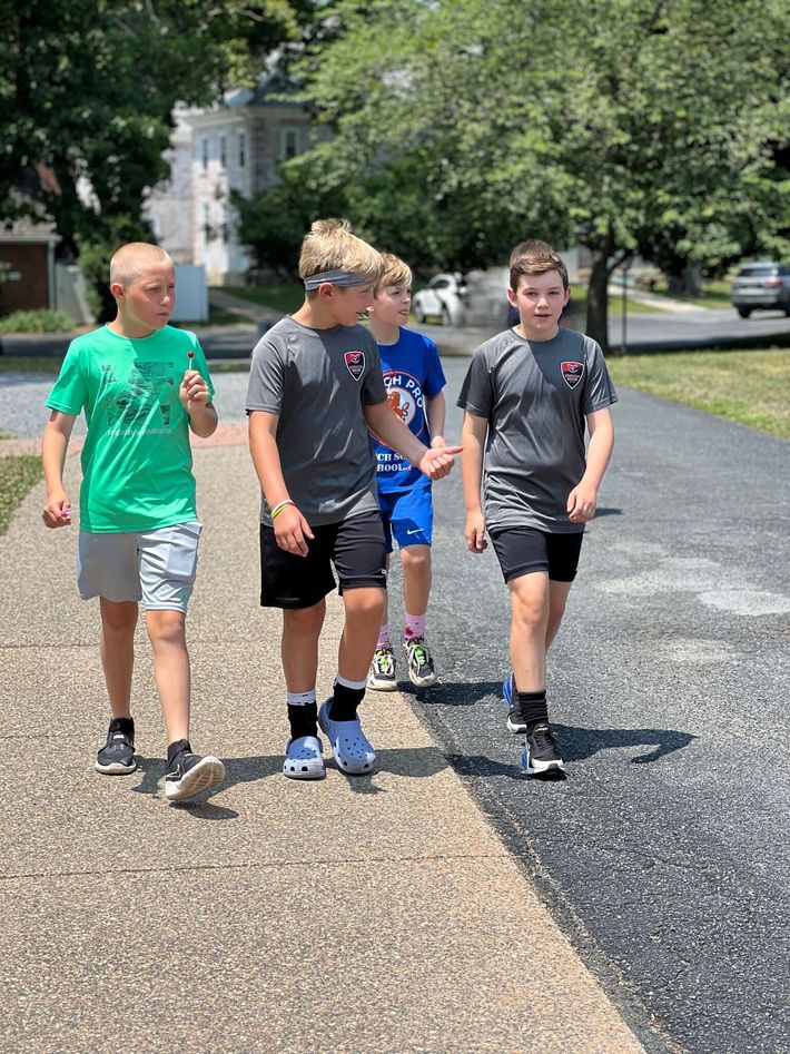A group of young Loudoun Soccer boys are walking down a sidewalk.