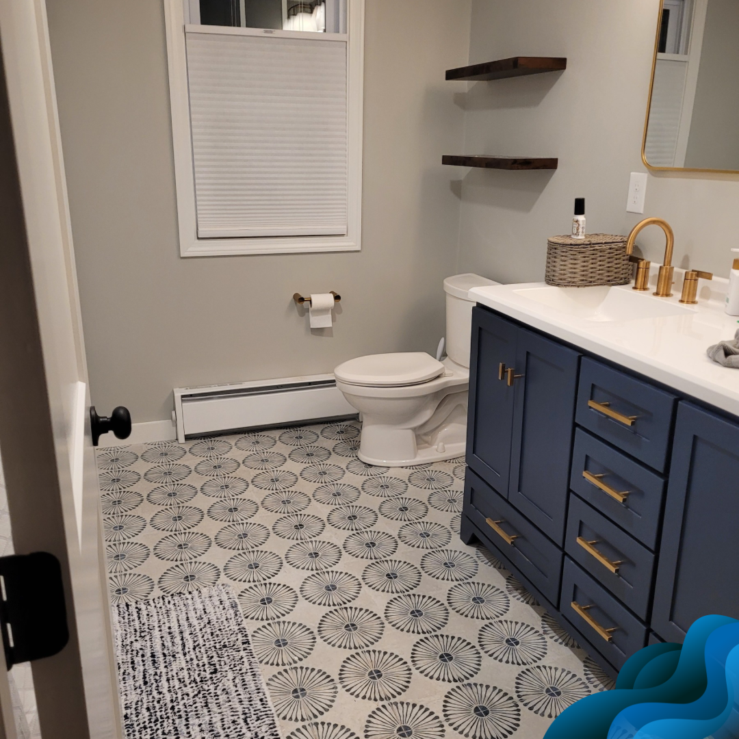 Bathroom with navy blue vanity, patterned tile floor, toilet, and shelves; light gray walls.