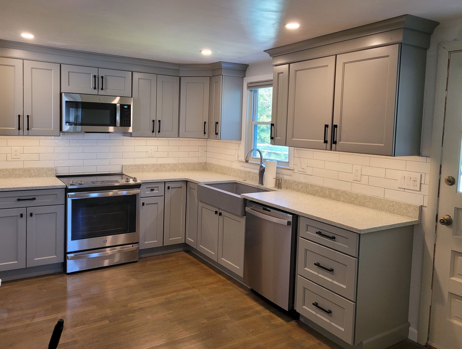 Gray kitchen cabinets with stainless steel appliances and white countertops.
