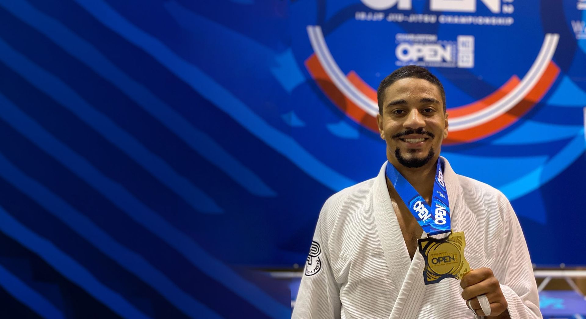 A man in a white kimono is holding a medal.