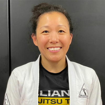 A woman in a karate uniform is smiling for the camera.