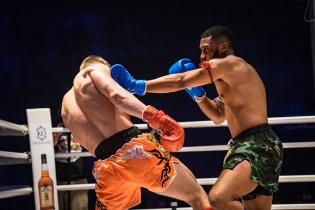 Two men are boxing in a ring with a bottle of whiskey in the background