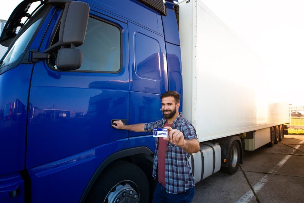 A Man In Front Of A Blue Semi Truck Holding A Driving License — Skilled Transport Training And Assessment in Woongarrah, NSW