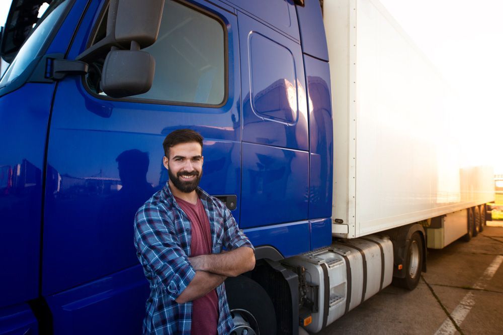 A Man Is Standing In Front Of A Blue Semi Truck — Skilled Transport Training And Assessment in Woongarrah, NSW