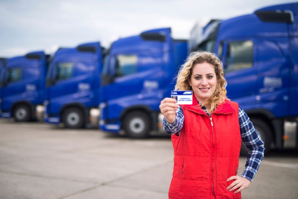 A Woman Holding A Driver 's License In Front Of A Blue Trucks — Skilled Transport Training And Assessment in Woongarrah, NSW