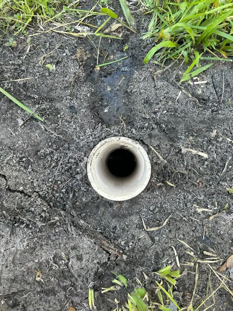 Woman in straw hat smiles, holding wine glass near a lake.