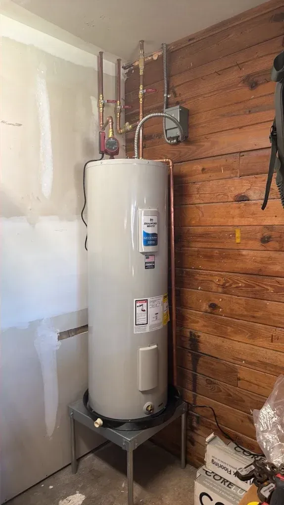 Woman in straw hat smiles, holding wine glass near a lake.