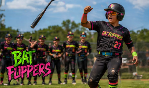 Youth baseball players in black and pink uniforms cheering on the field, with a bat flipping in the air.
