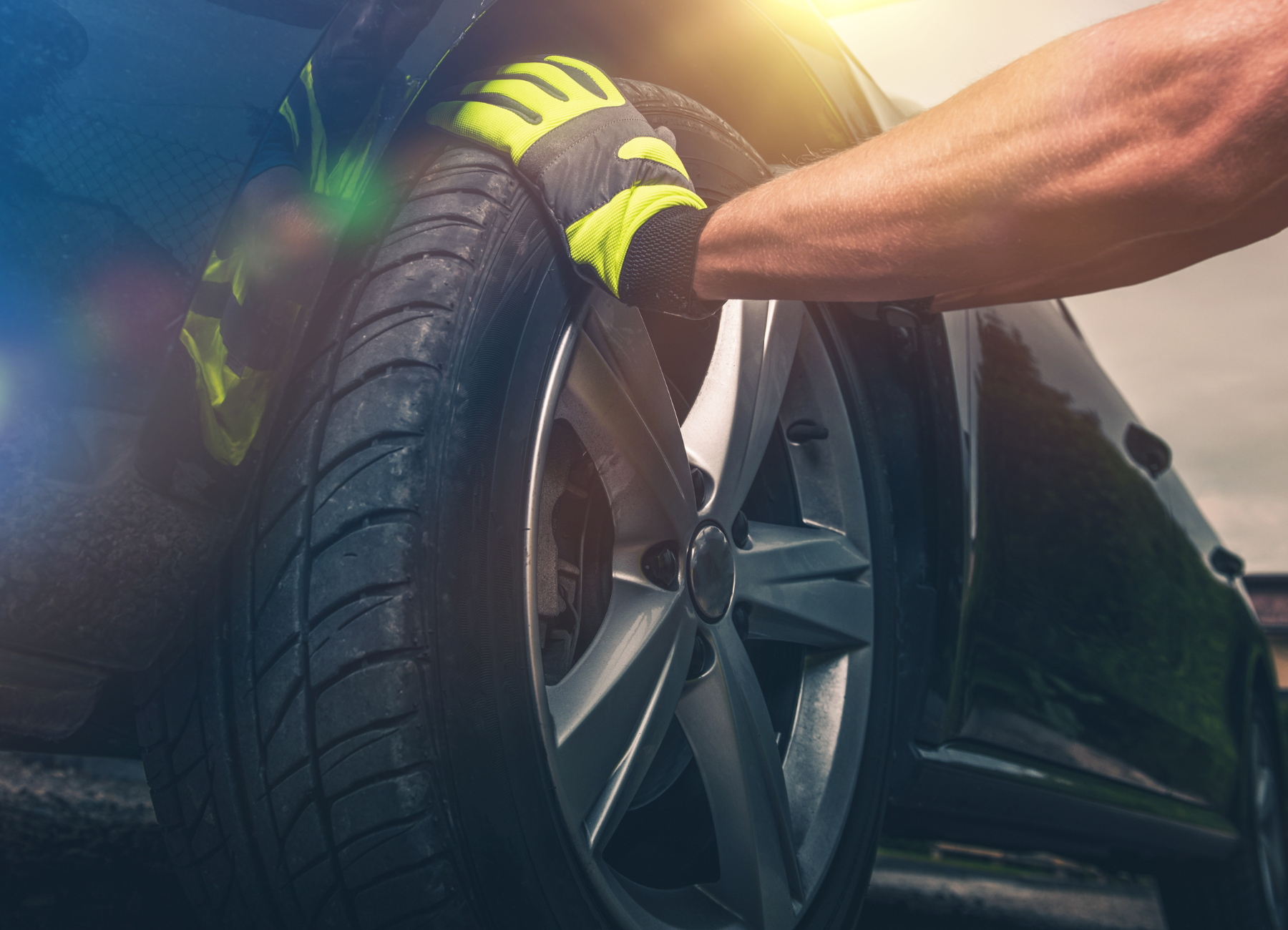 a person wearing gloves is changing a tire on a car