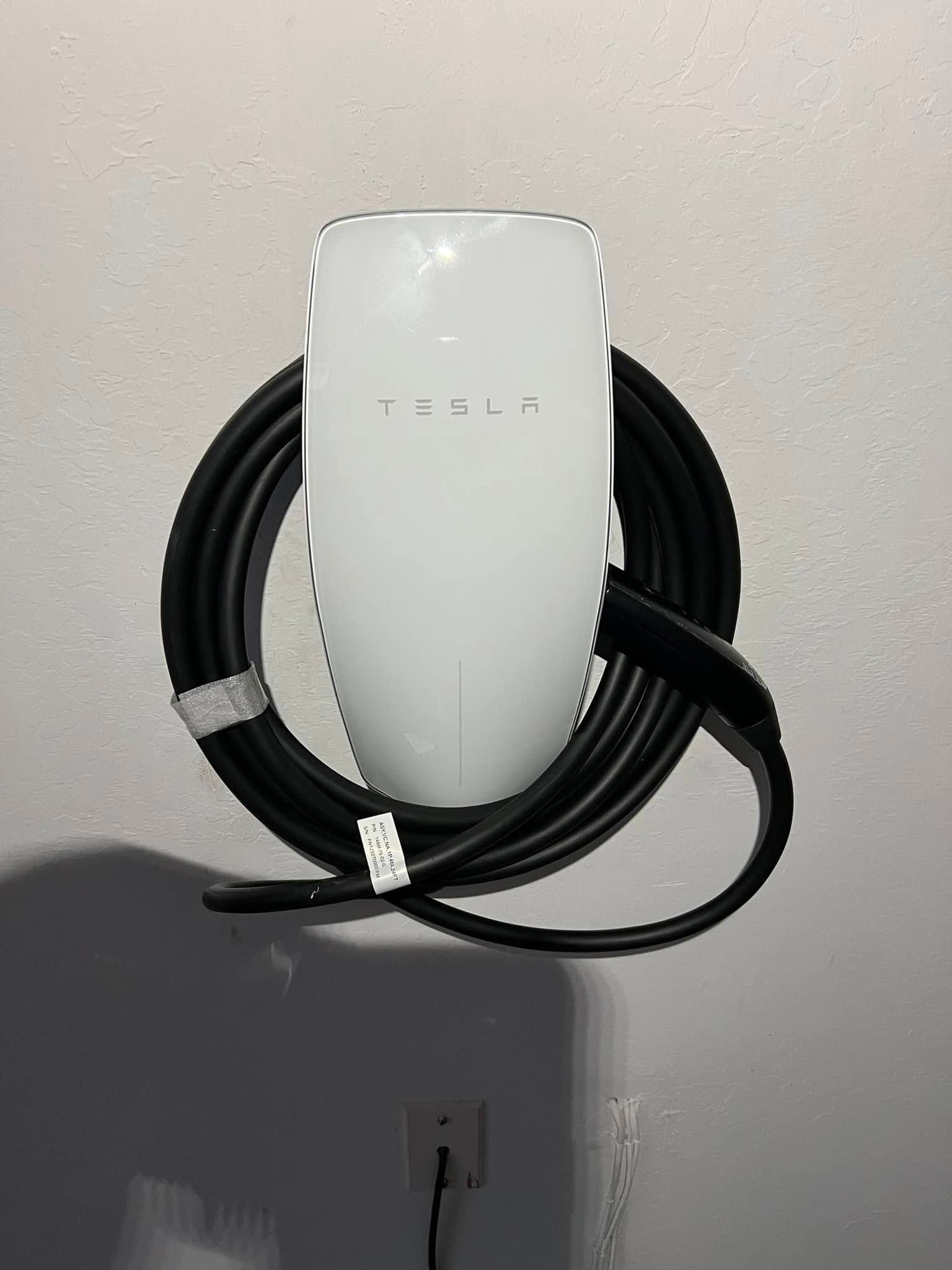 A tesla charging station with a black cable attached to it