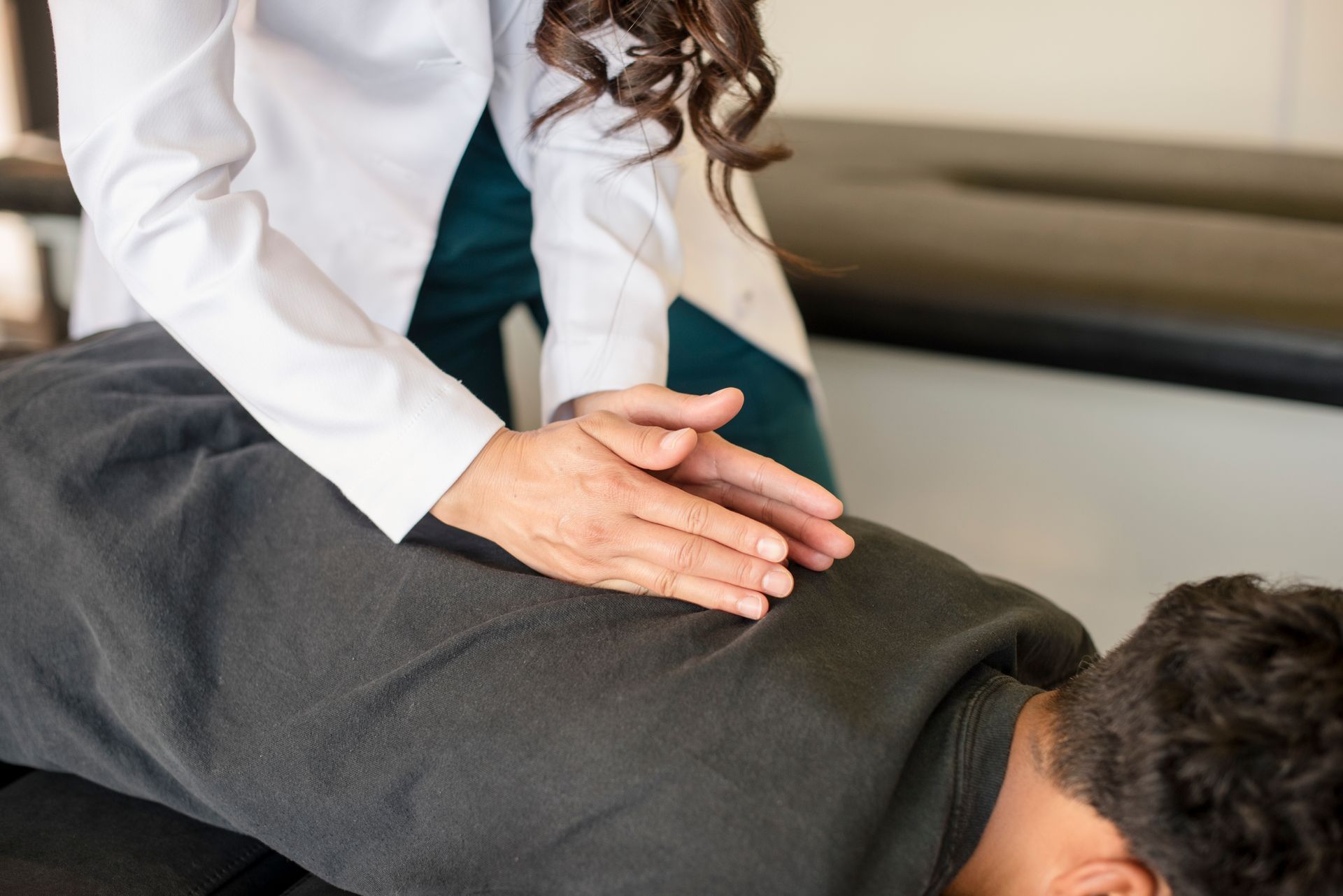 Chiropractor pressing on a patient’s lower back during an adjustment session