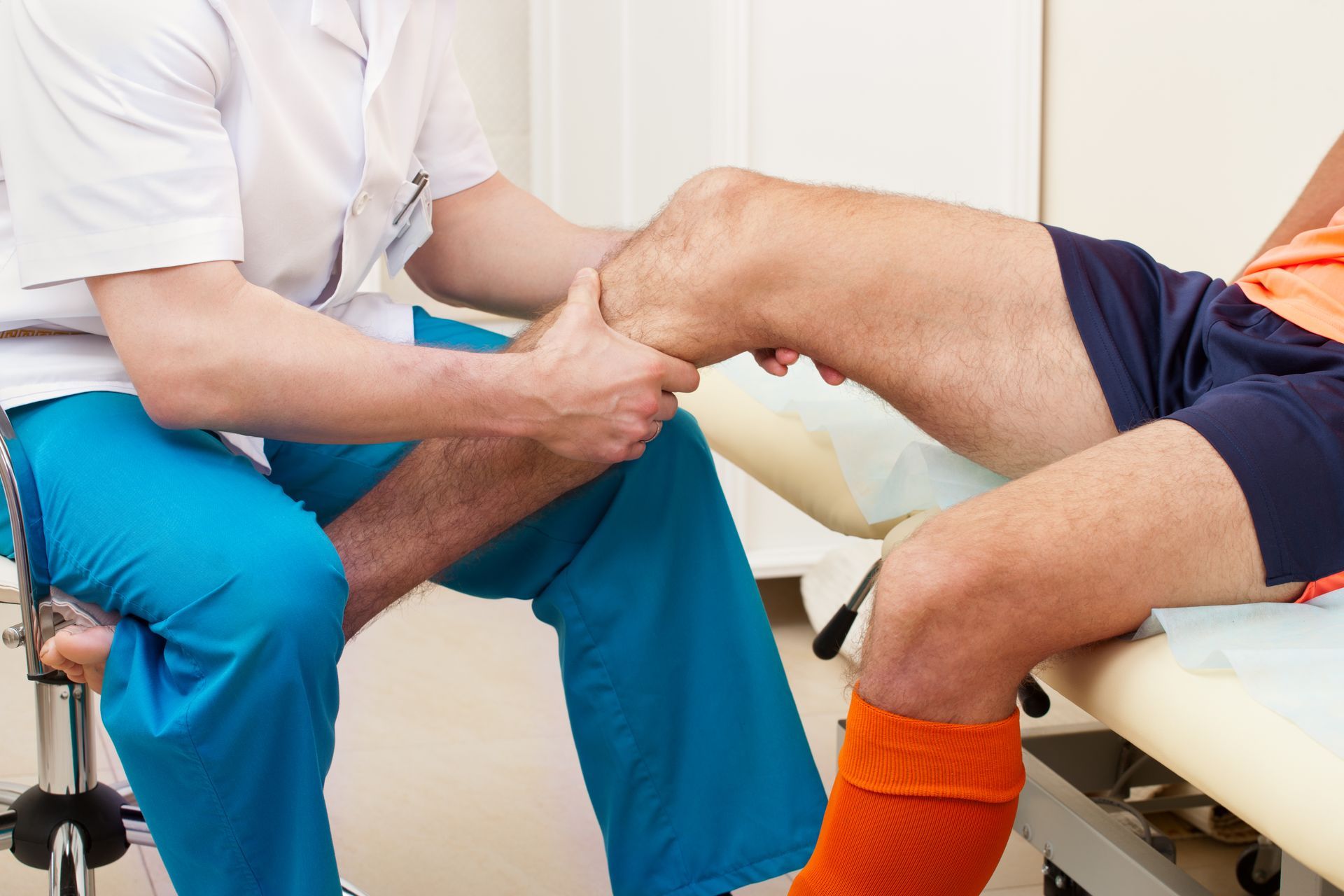 Physical therapist examining a patient's knee during a clinic session