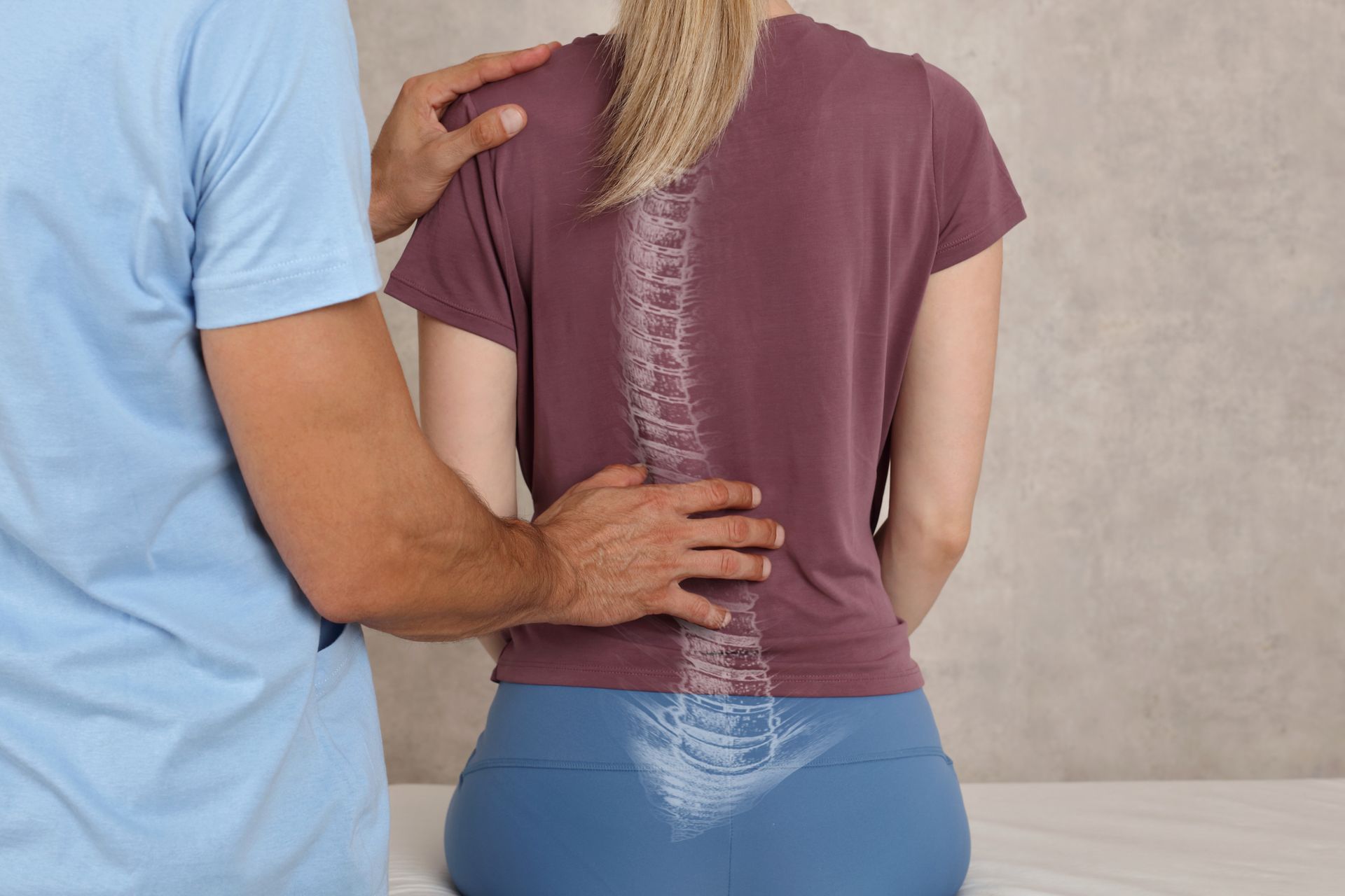 Chiropractor examining a woman’s spine with hands on her back in a clinic setting
