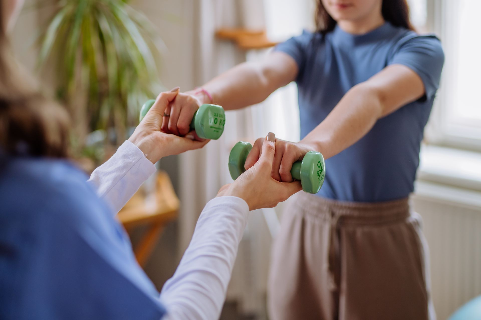 People exercising with small green dumbbells in a bright indoor room