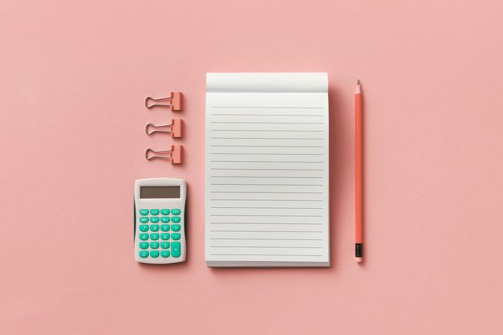 A notepad with a calculator, three binder clips and a pencil