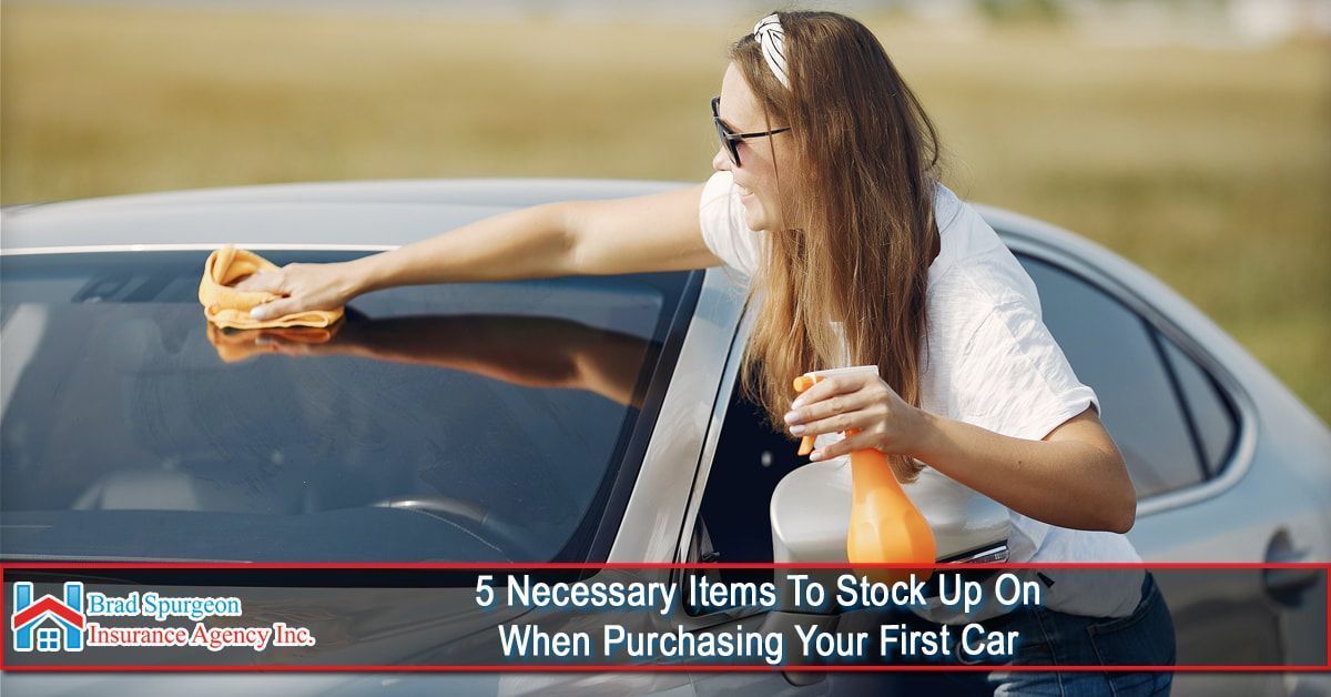 A person cleaning a car windshield with a yellow cloth and spray bottle