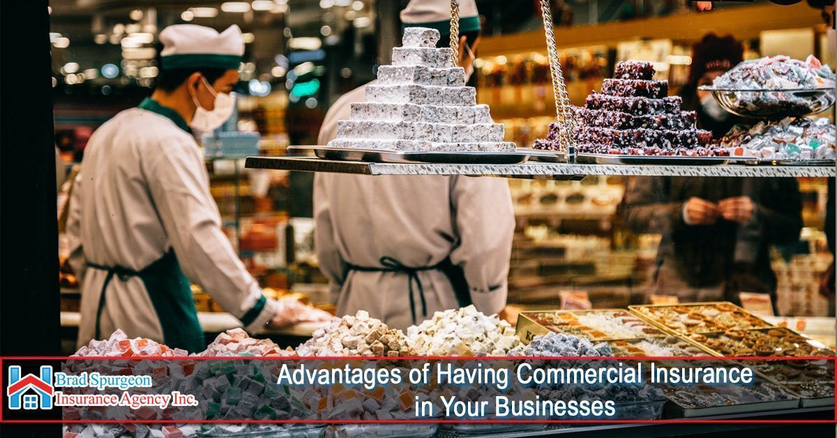 Two workers in a shop stand behind a display of stacked sweets.