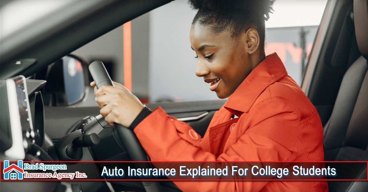 A person in an orange jacket sits in the driver's seat of a car
