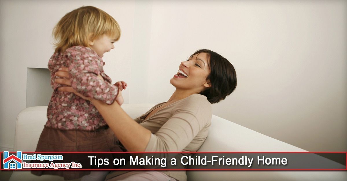 A woman laughs while holding a small child on a white sofa