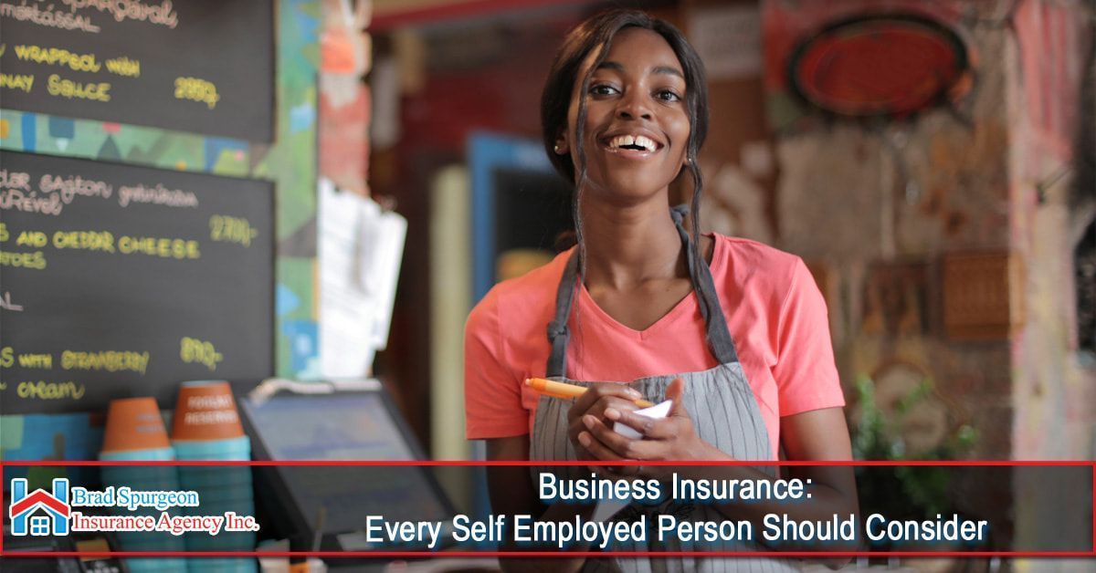 A person in a cafe apron smiling while holding a notebook