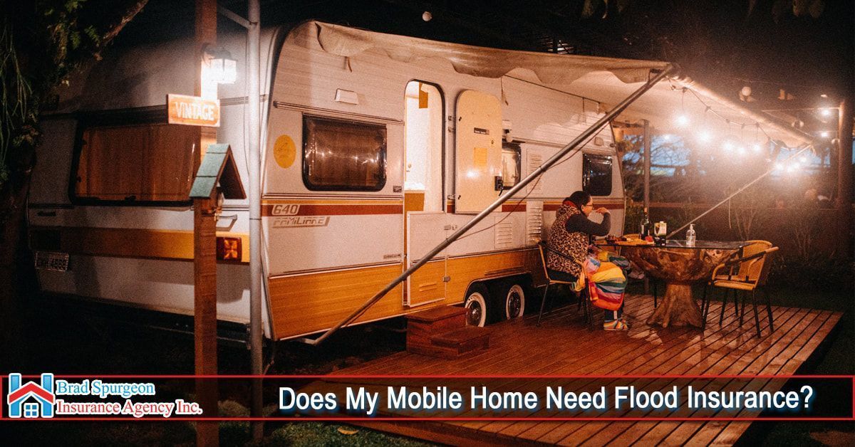 A camper trailer park on a wooden deck at night with a person sitting at an outdoor table under string lights.