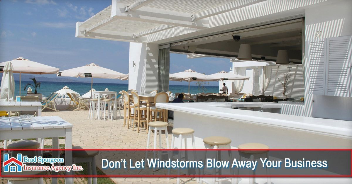 A white, open-air beach bar with stools under a pergola. 