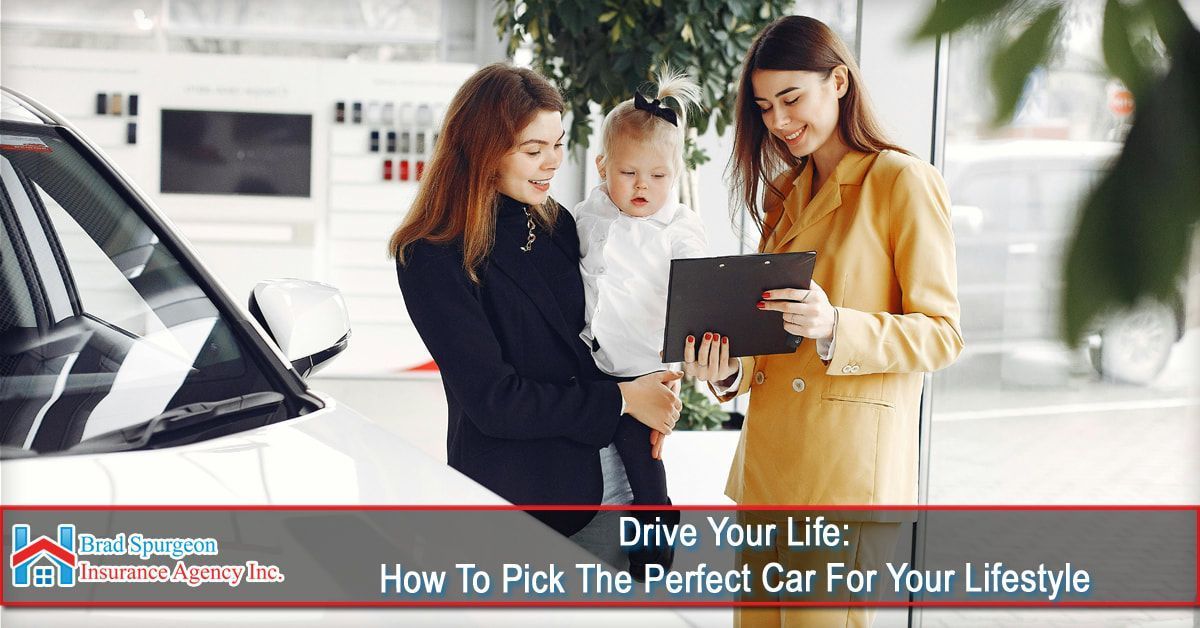 A car salesperson shows a clipboard to a person holding a small child in a car dealership showroom.