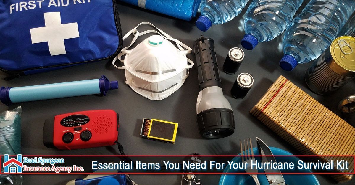 A collection of hurricane survival kit supplies, including water bottles, a first aid bag, mask, flashlight, and food.
