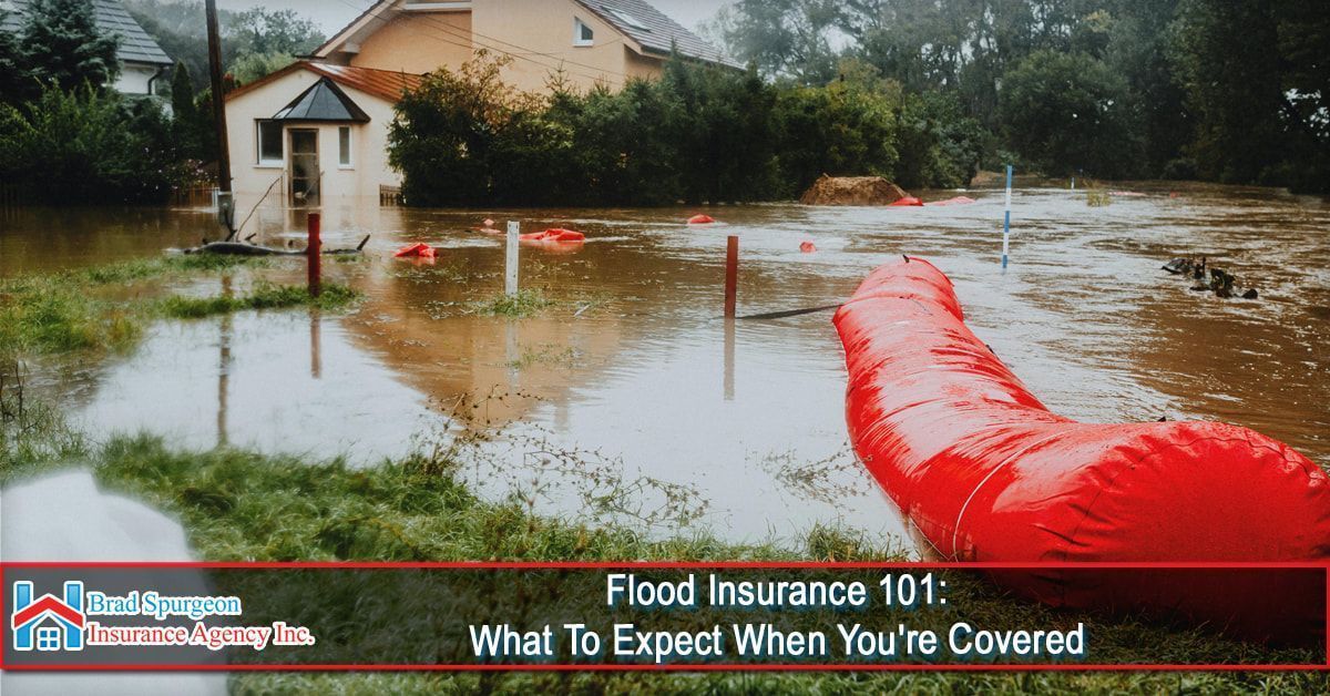 A flooded yard near a house with a long, red inflatable flood barrier in the foreground