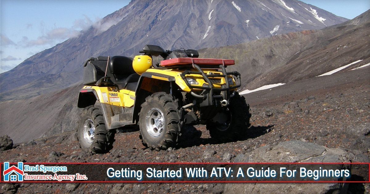 A yellow ATV parked on a rocky mountainside with snow in the background