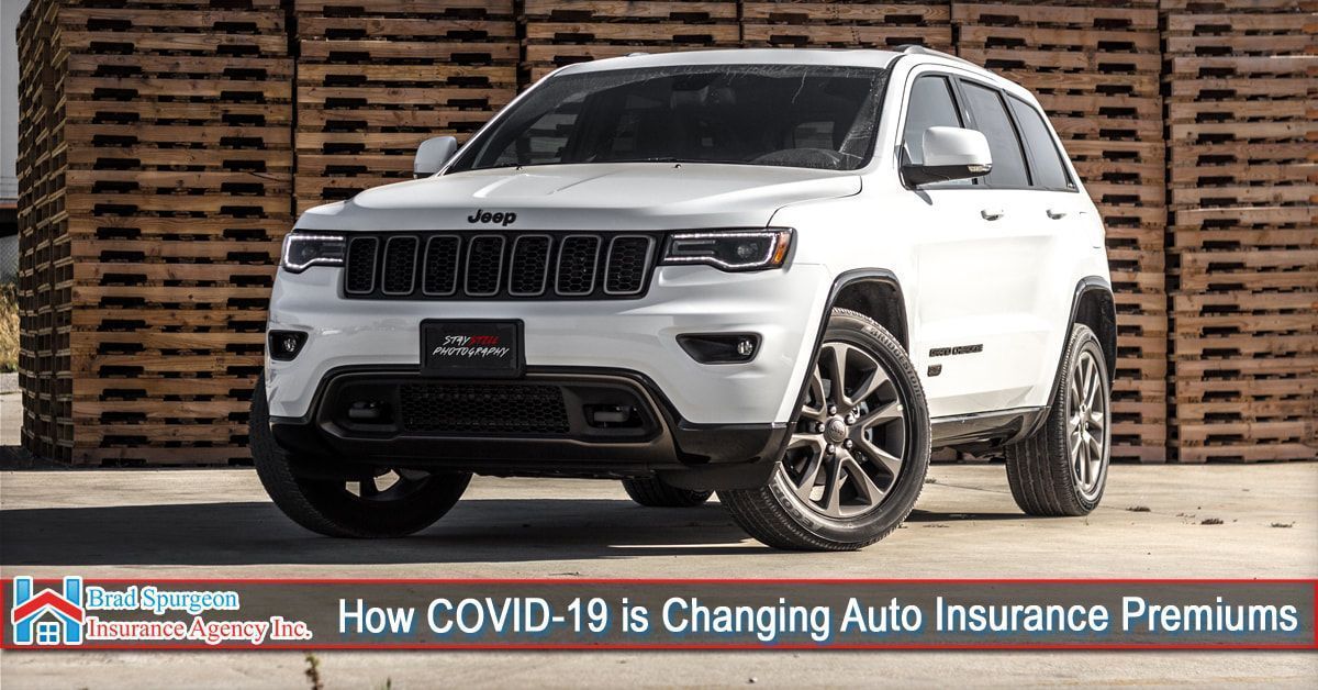 A white Jeep SUV parked in front of a stack of wooden pallets