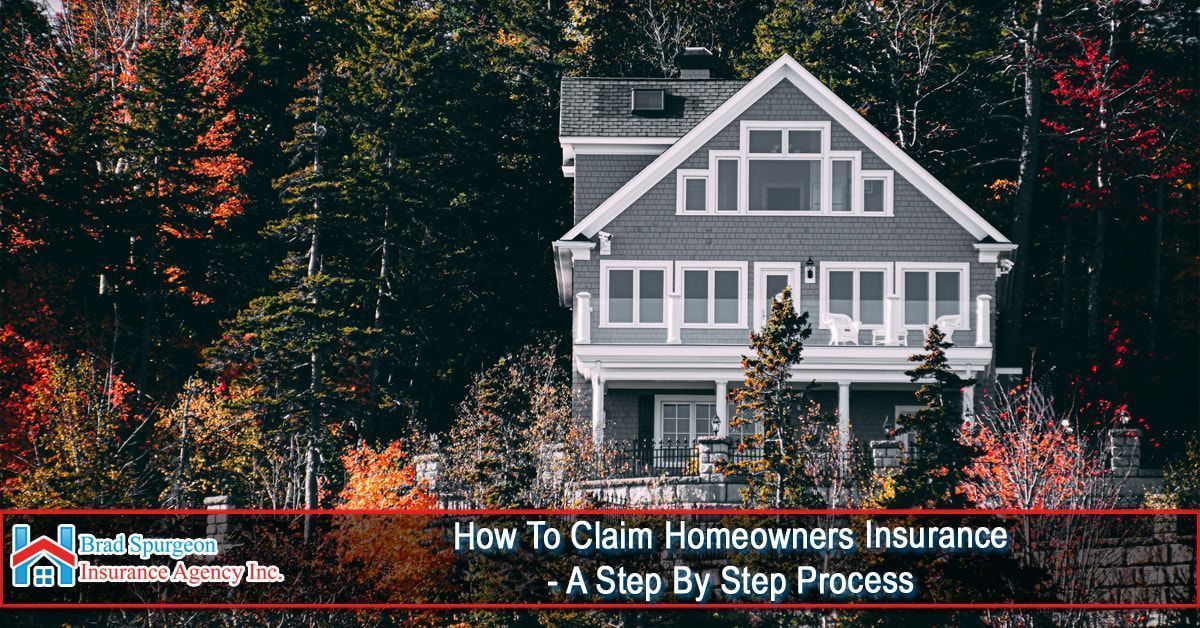 A gray, two-story house nestled among autumn trees 
