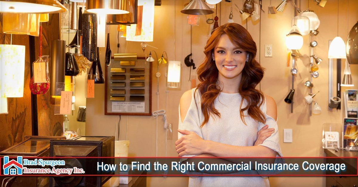 A smiling woman stands with arms crossed in a brightly lit store filled with various hanging light fixtures.