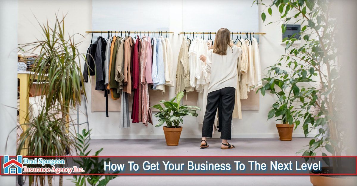 A person organizes clothes on a rack in a room filled with potted plants
