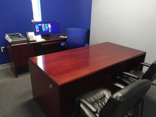 Office with mahogany desk, two black chairs, computer, printer, blue and white walls.